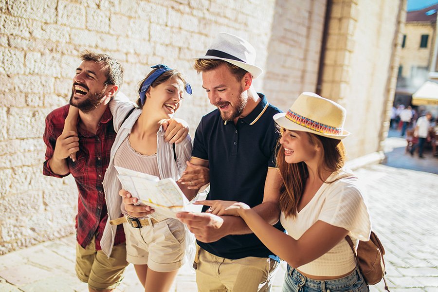 Home group of tourists searching for places on their map outdoors.